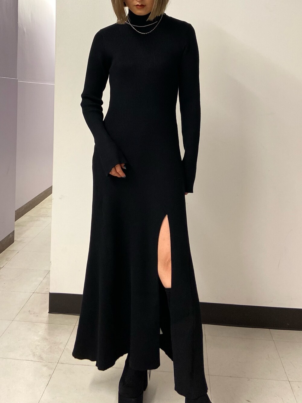 ブラック系のワンピース、ホワイト系のショルダーバッグ、ブラック系のブーツを着用したレディースの秋コーディネートの5枚目の写真