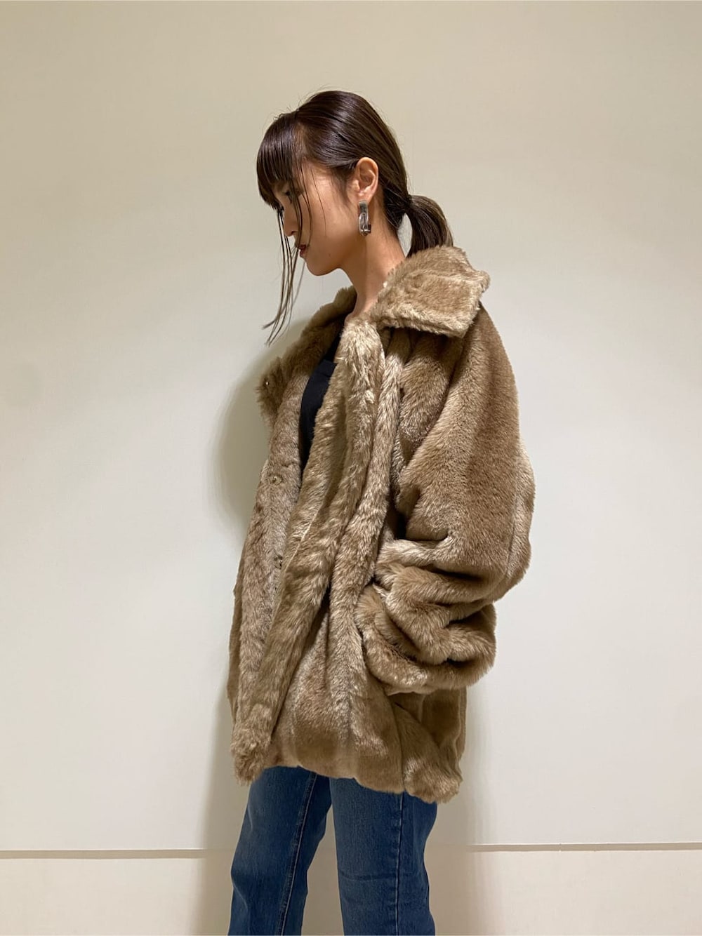 ブルー系のデニムパンツ、ブラック系のブーツ、ベージュ系のその他アウターを着用したレディースの冬コーディネートの3枚目の写真