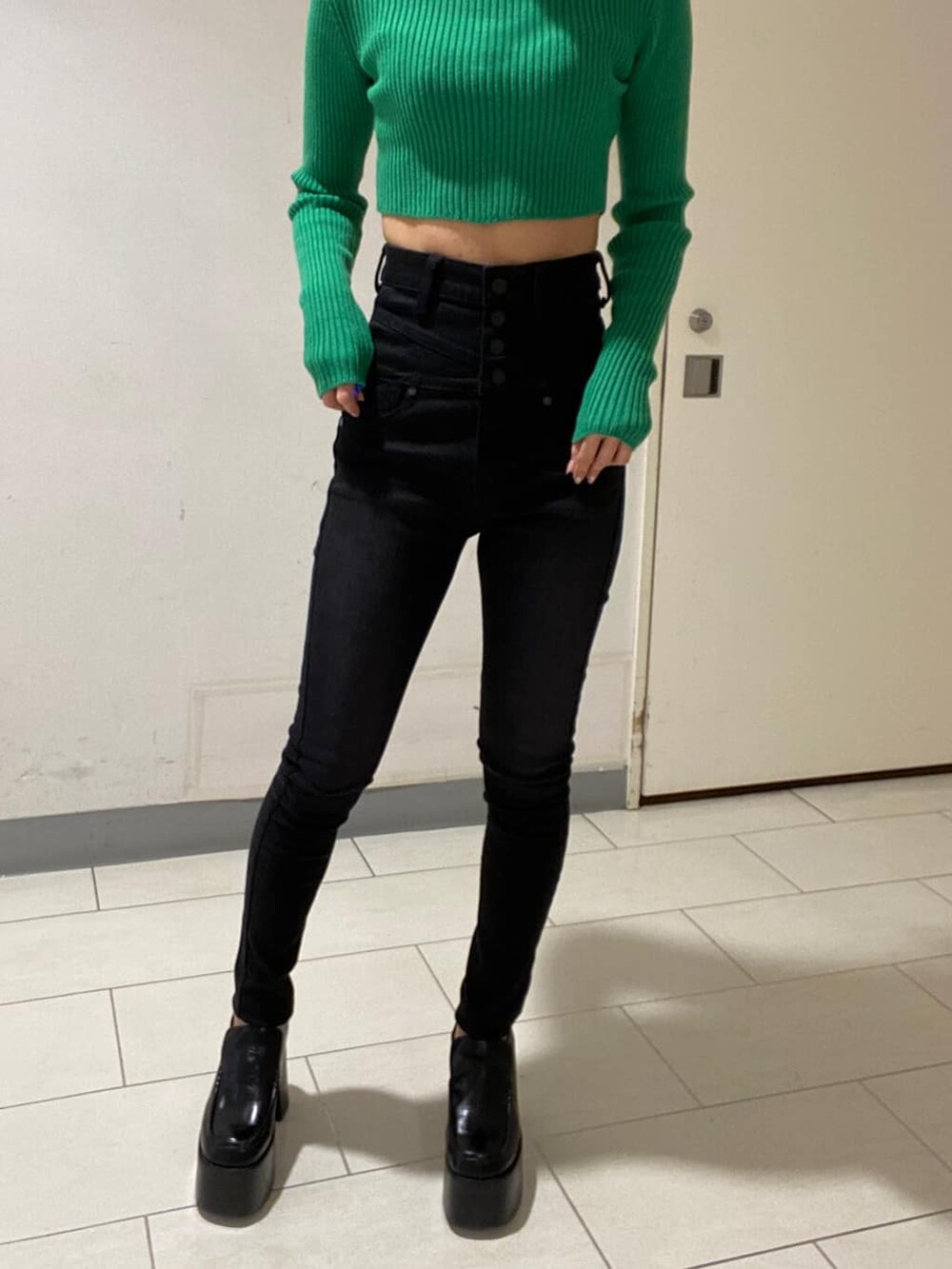 ブラック系のローファー、グリーン系のニット/セーター、ブラック系のデニムパンツを着用したレディースの冬コーディネートの4枚目の写真