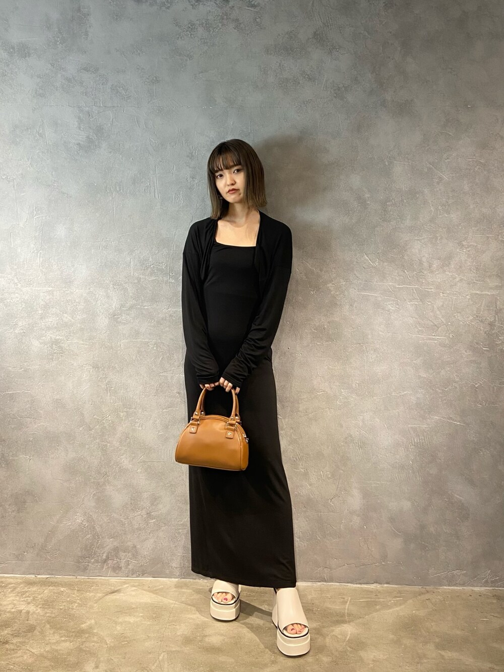 ブラック系のワンピース、ブラック系のハンドバッグ、ホワイト系のサンダルを着用したレディースの春コーディネートの2枚目の写真