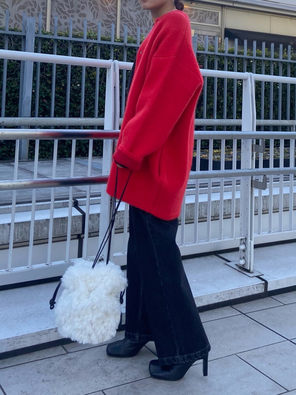 レッド系のカーディガン/ボレロ、ブラック系のデニムパンツ、ブラック系のブーツを着用したレディースの冬コーディネートの2枚目の写真