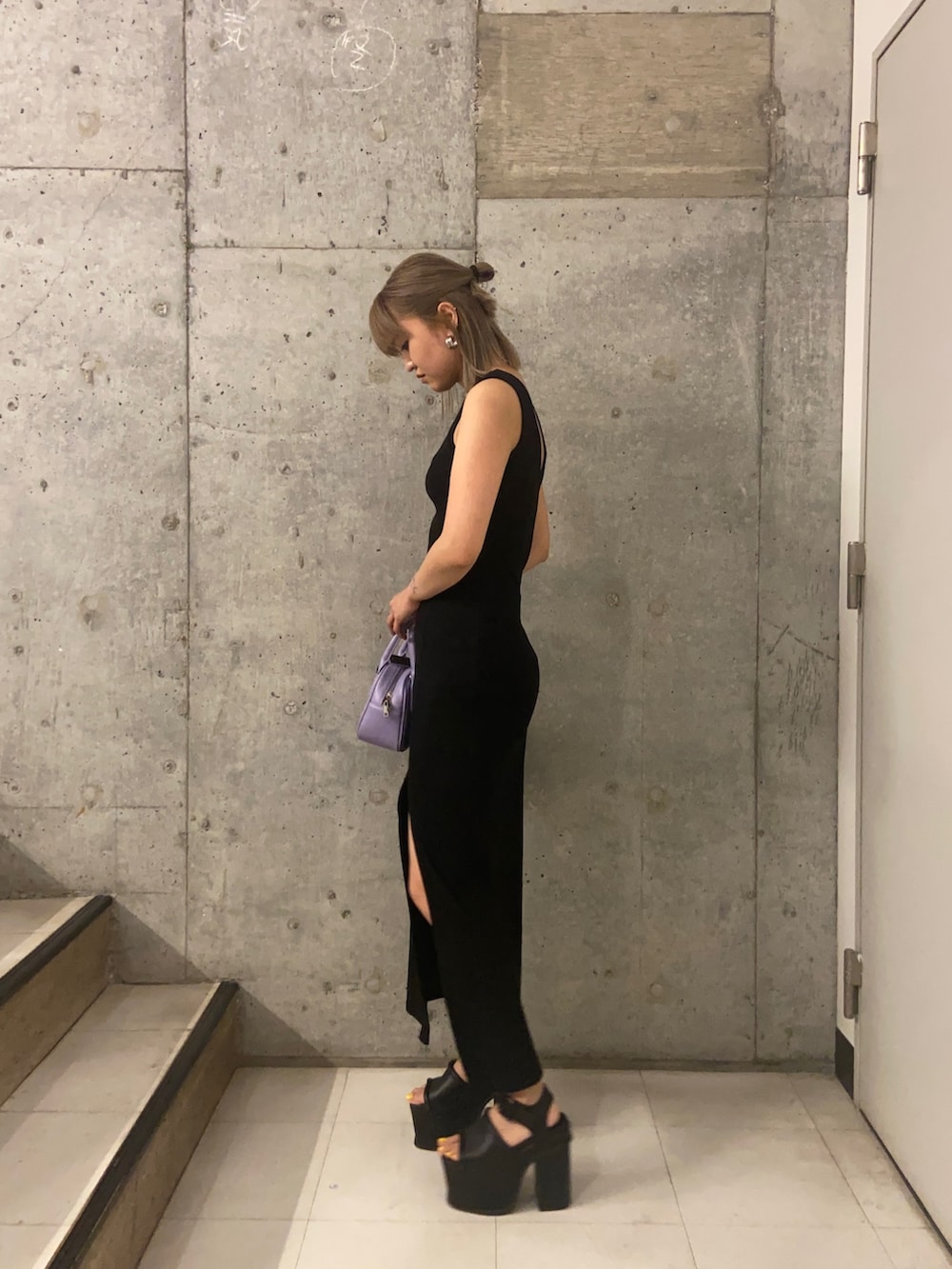 ブラック系のワンピース、パープル系のハンドバッグ、ブラック系のサンダルを着用したレディースの春コーディネートの2枚目の写真