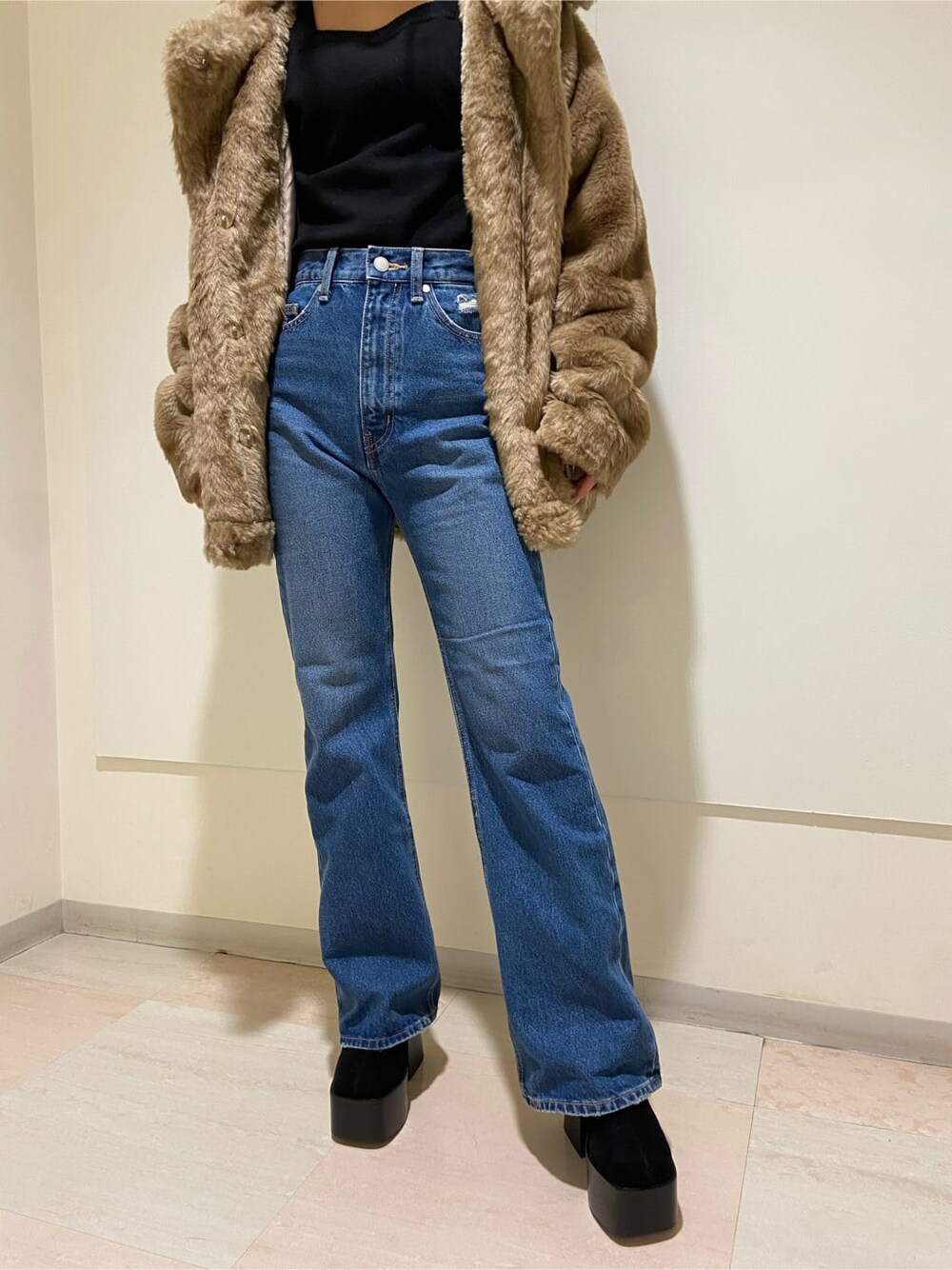 ブルー系のデニムパンツ、ブラック系のブーツ、ベージュ系のその他アウターを着用したレディースの冬コーディネートの5枚目の写真