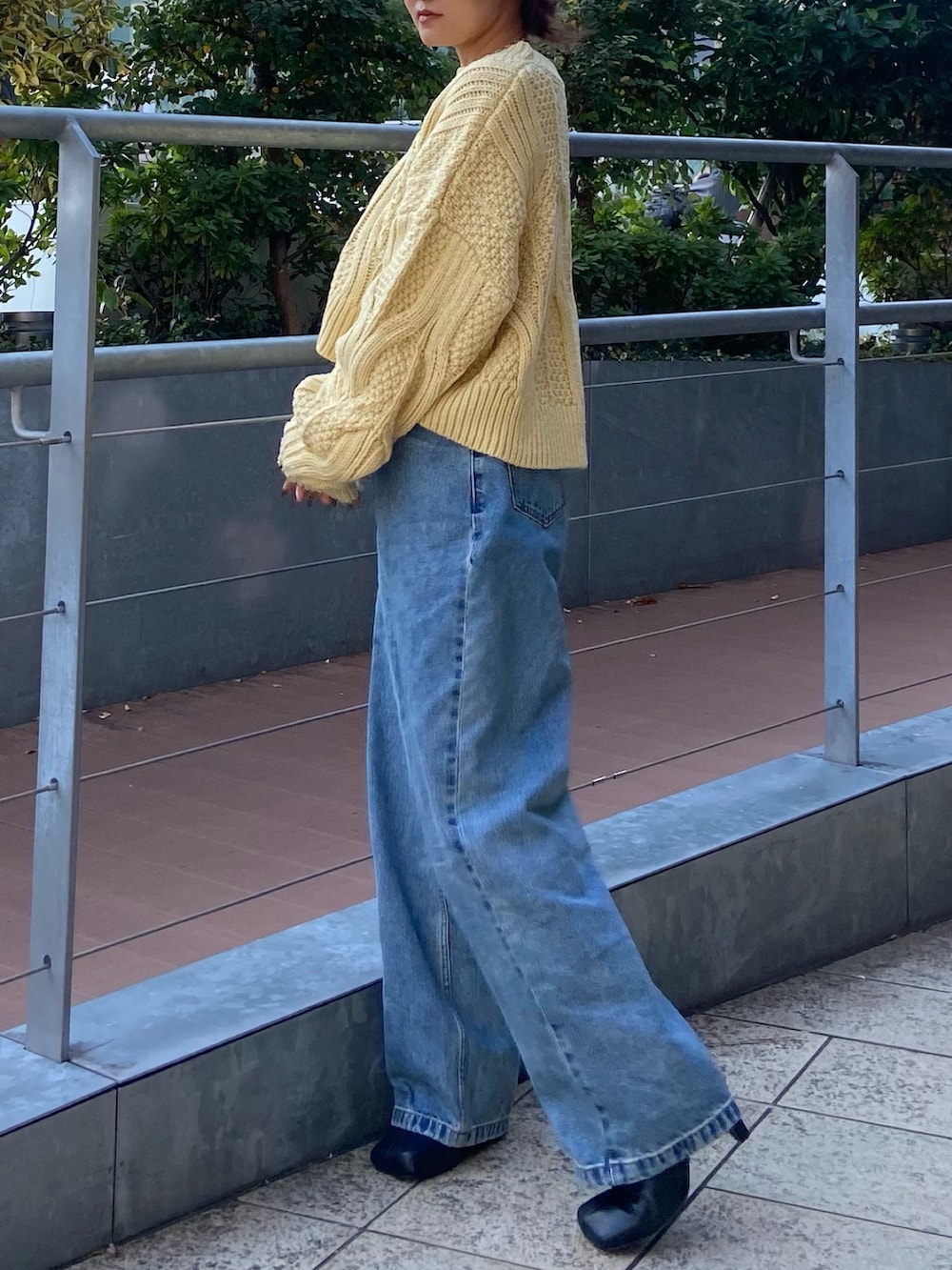 ブルー系のデニムパンツ、ブラック系のブーツ、イエロー系のニット/セーターを着用したレディースの冬コーディネートの2枚目の写真