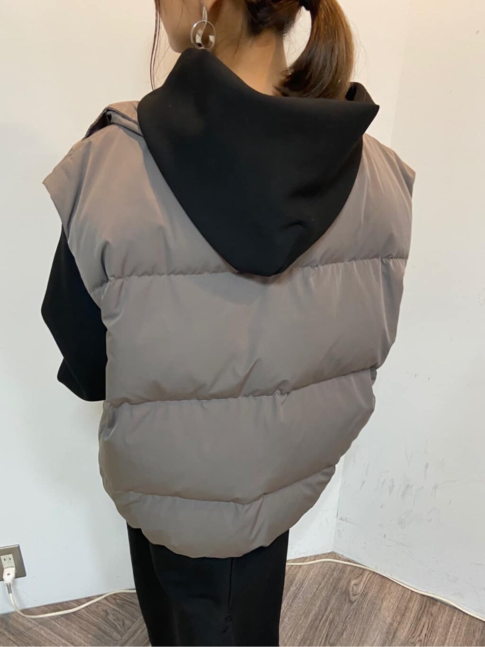 グレー系のダウンベスト、ブラック系のワンピースを着用したレディースの秋コーディネートの4枚目の写真