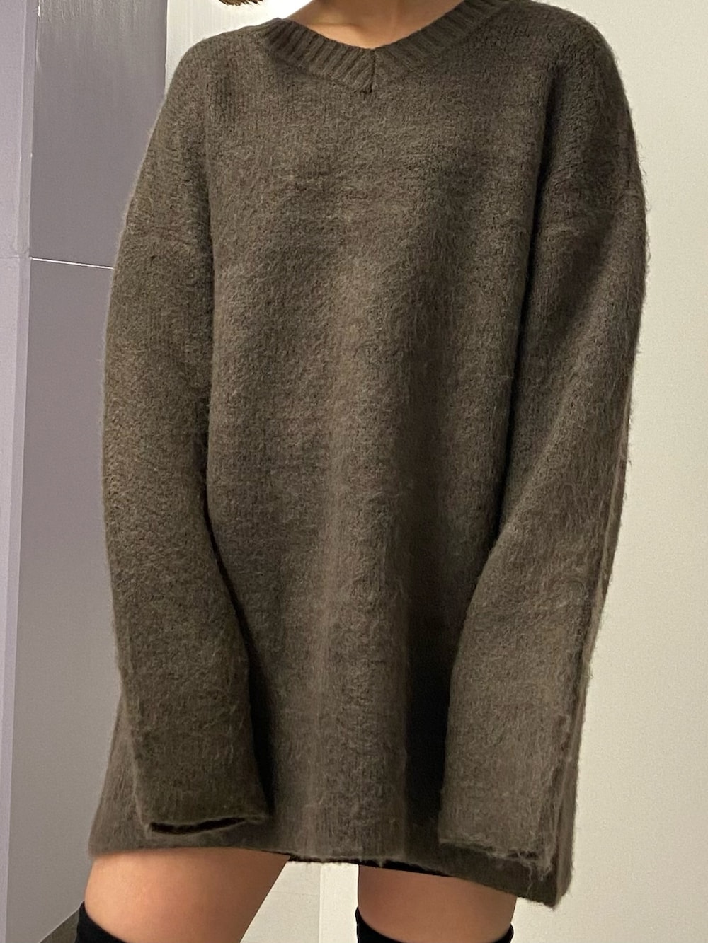 ブラウン系のニット/セーター、ブラック系のスカート、ブラック系のブーツを着用したレディースの冬コーディネートの6枚目の写真