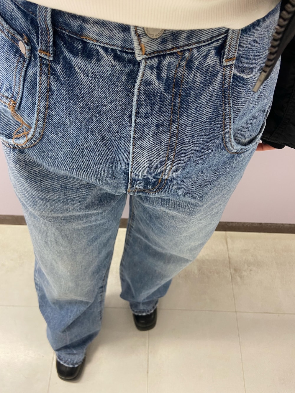 ブルー系のデニムパンツ、ブラック系のブーツ、ホワイト系のスウェットを着用したレディースの秋コーディネートの6枚目の写真