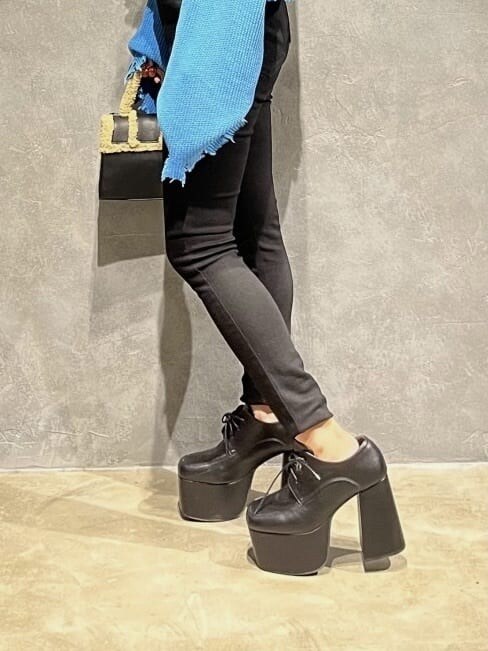 ブラック系のデニムパンツ、ブラック系のハンドバッグ、ブルー系のカーディガン/ボレロを着用したレディースの秋コーディネートの7枚目の写真