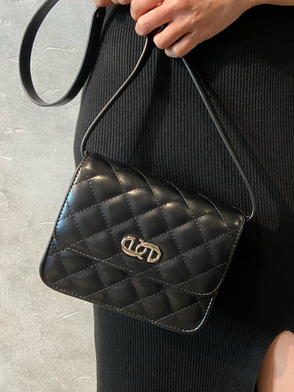 ブラック系のワンピース、ブラック系のショルダーバッグ、ホワイト系のサンダルを着用したレディースの春コーディネートの7枚目の写真