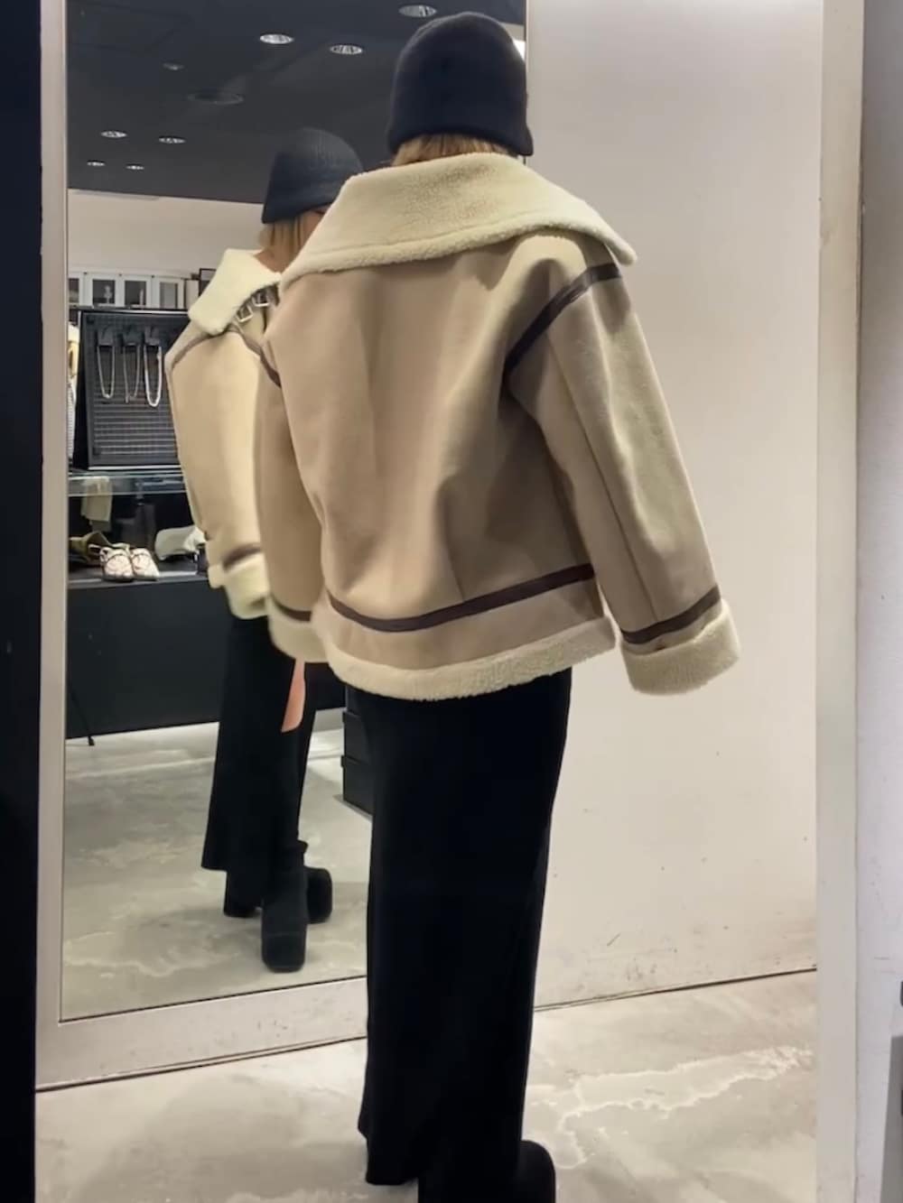 ベージュ系のブルゾン、ブラック系のワンピース、ブラック系のブーツを着用したレディースの冬コーディネートの3枚目の写真