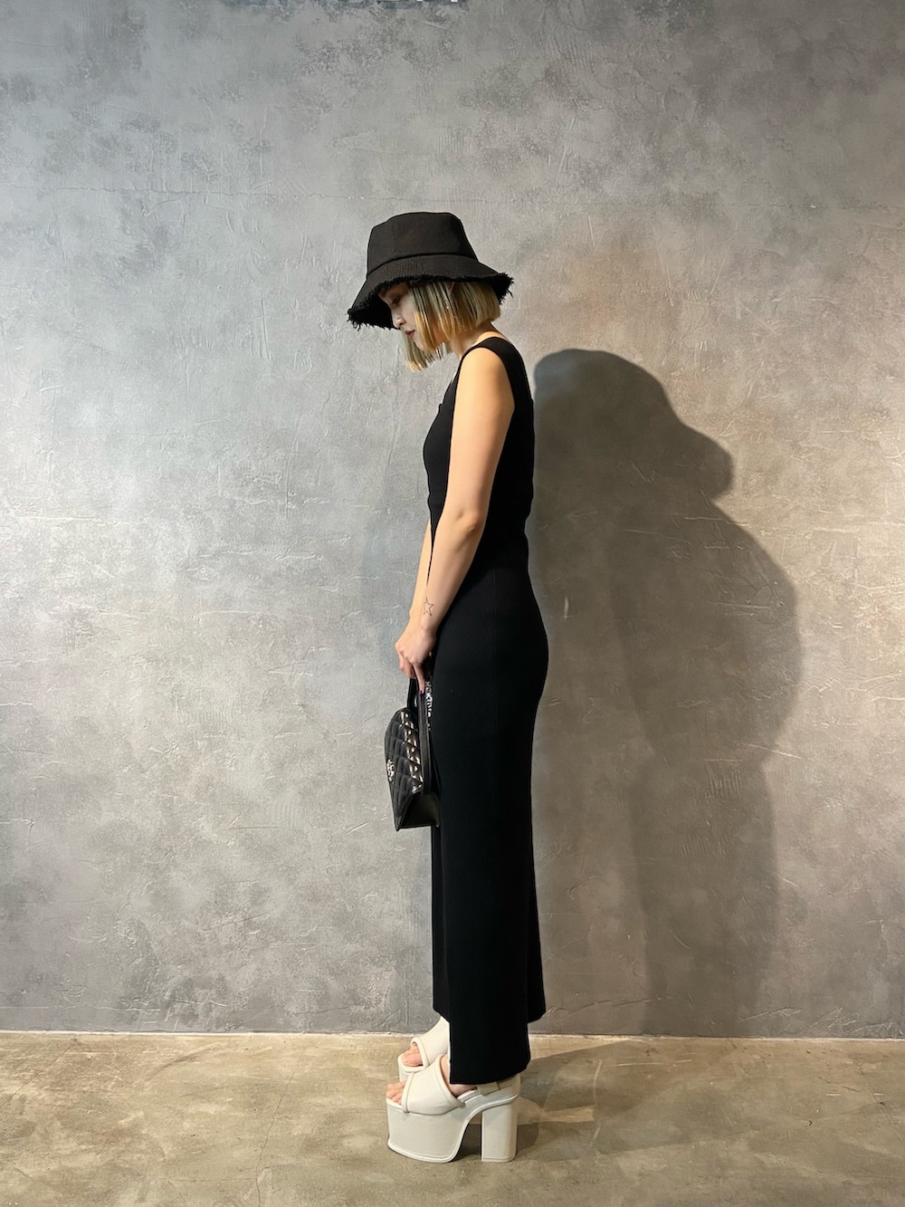 ブラック系のワンピース、ブラック系のショルダーバッグ、ホワイト系のサンダルを着用したレディースの春コーディネートの2枚目の写真