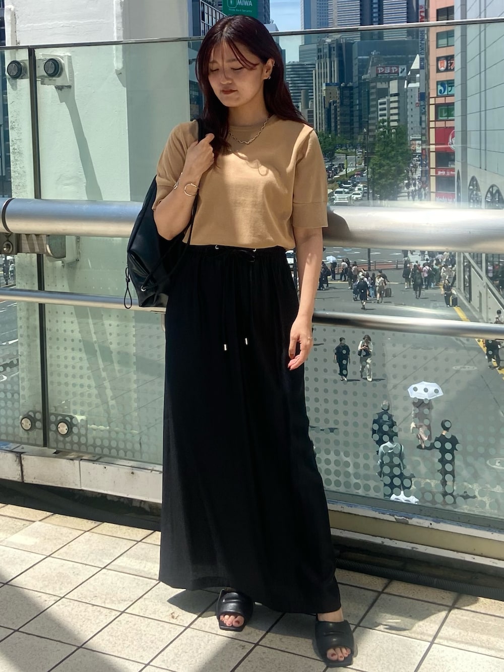 ブラック系のスカート、ブラック系のサンダル、ベージュ系のニット/セーターを着用したレディースの夏コーディネートの2枚目の写真