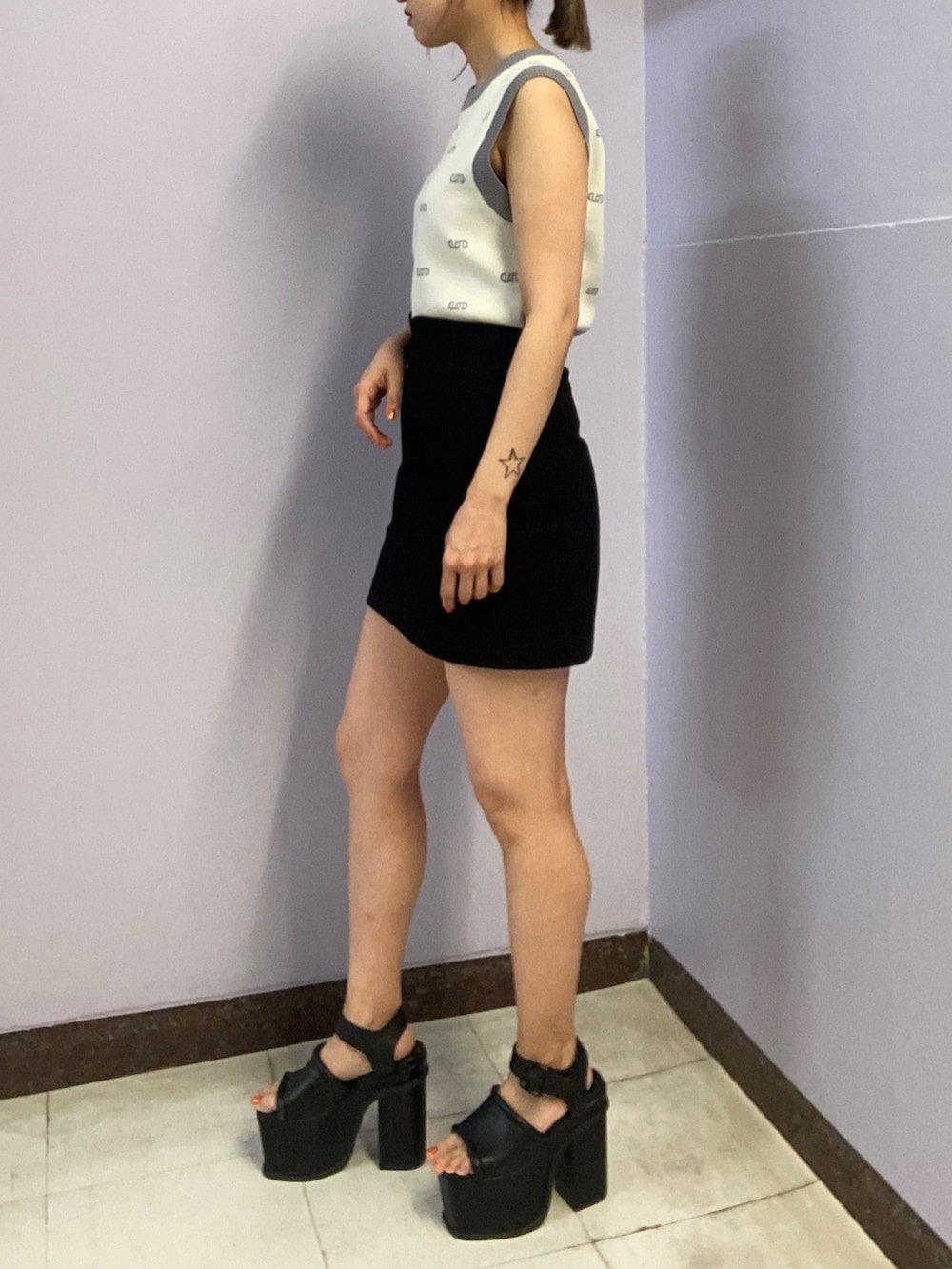 ホワイト系のニット/セーター、ブラック系のスカート、ブラック系のサンダルを着用したレディースの春コーディネートの2枚目の写真