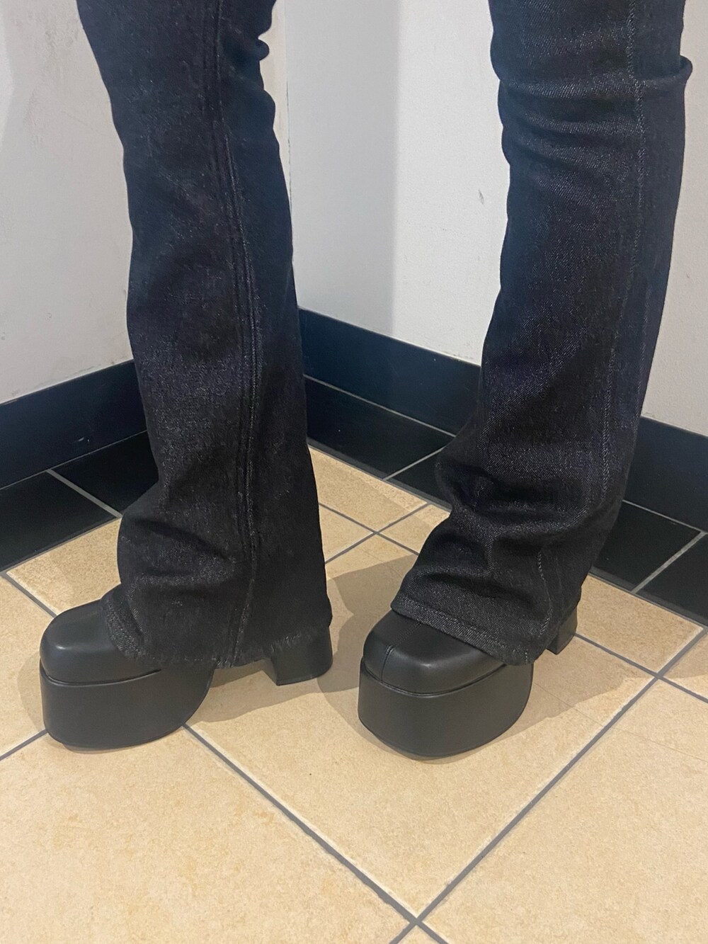 グレー系のニット/セーター、ブラック系のデニムパンツ、ブラック系のブーツを着用したレディースの秋コーディネートの6枚目の写真