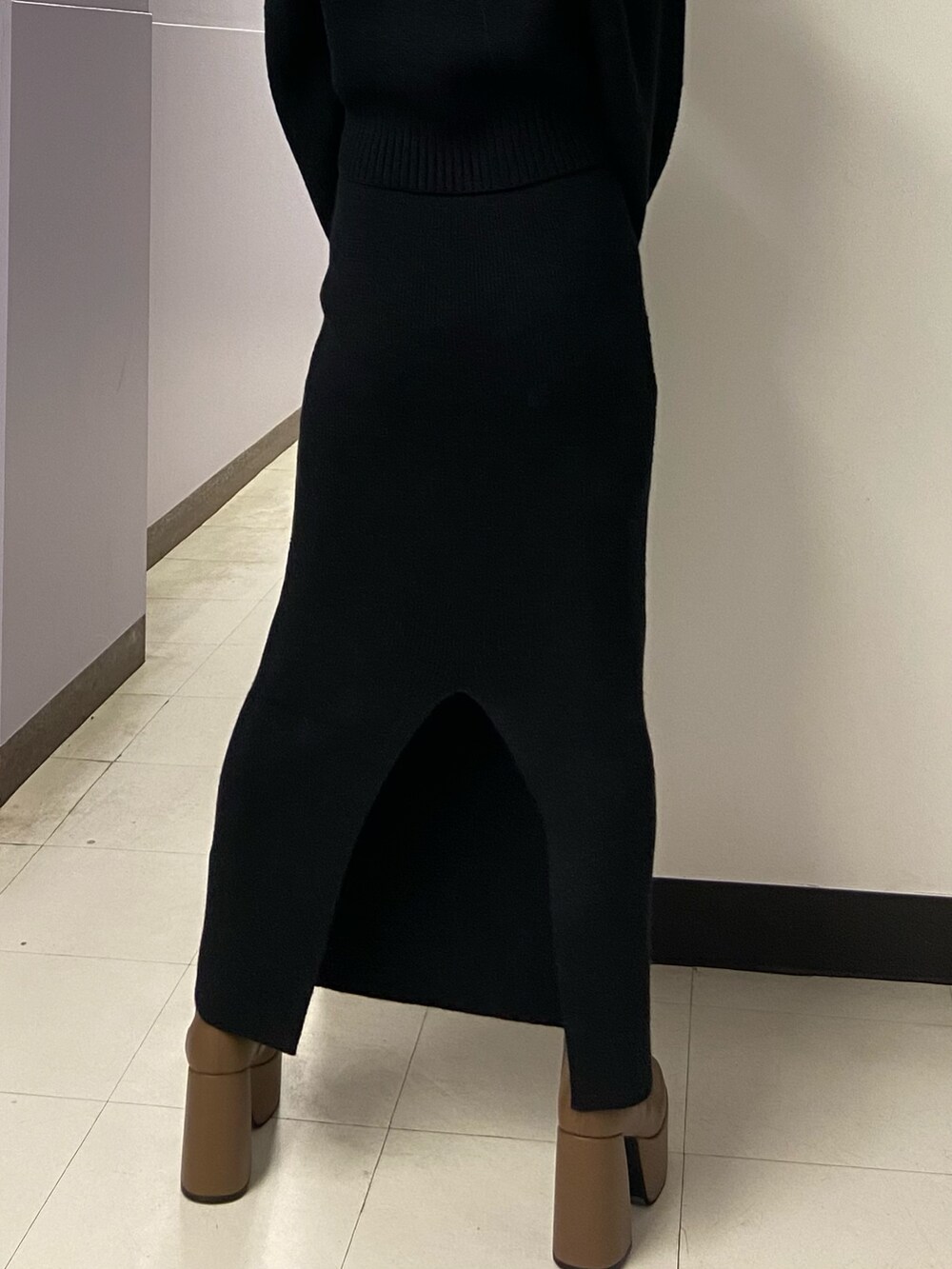 ブラック系のニット/セーター、ブラウン系のブーツ、ブラック系のスカートを着用したレディースの冬コーディネートの7枚目の写真