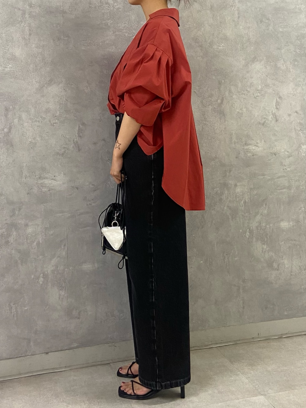 オレンジ系のシャツ/ブラウス、ブラック系のサンダル、ブラック系のデニムパンツを着用したレディースの夏コーディネートの3枚目の写真