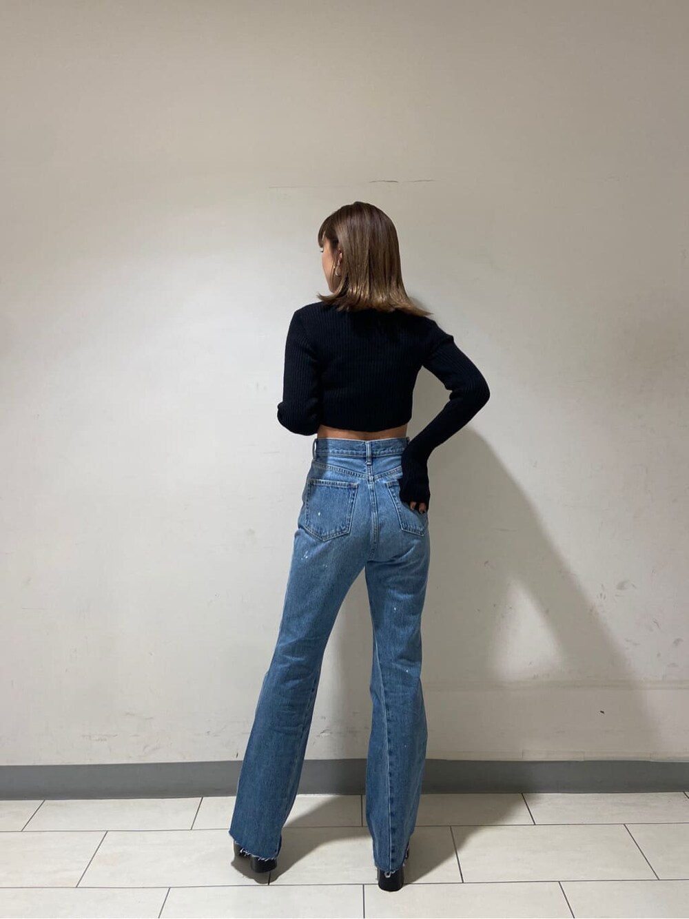 ブラック系のニット/セーター、ブルー系のデニムパンツ、ブラック系のローファーを着用したレディースの冬コーディネートの2枚目の写真