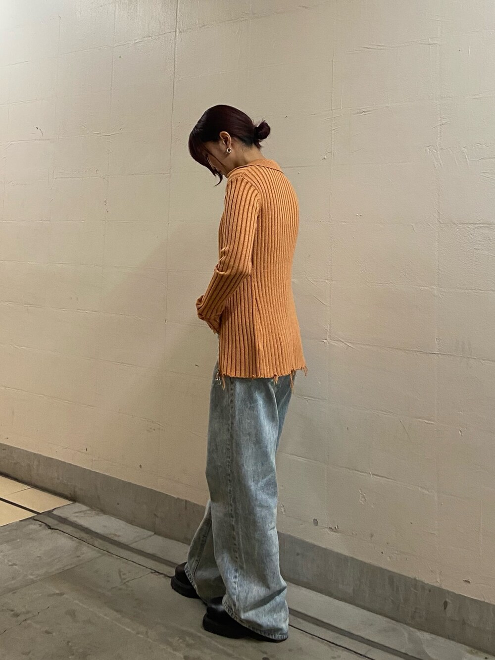 オレンジ系のニット/セーター、ブラック系のキャミソール、ブルー系のデニムパンツを着用したレディースの春コーディネートの2枚目の写真
