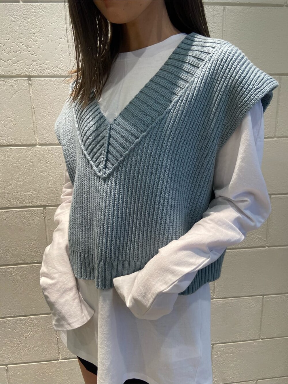 ブラック系のスカート、ブラック系のブーツ、ブルー系のベストを着用したレディースの春コーディネートの5枚目の写真