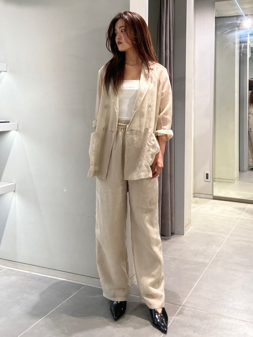 ホワイト系のテーラードジャケット、ホワイト系のその他パンツ、ブラック系のパンプスを着用したレディースの春コーディネートの2枚目の写真