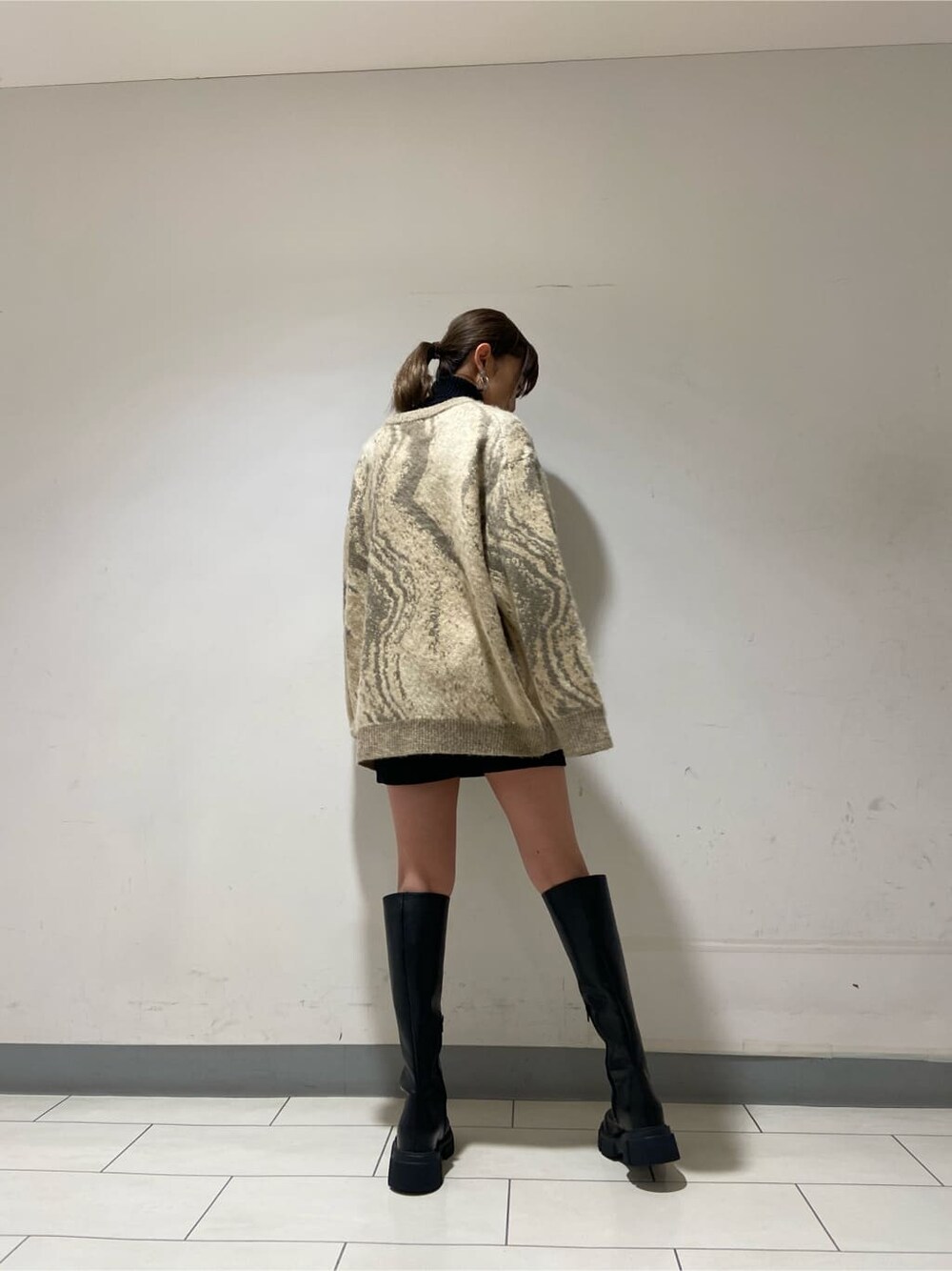 ブラック系のブーツ、ブラック系のスカート、ブラック系のニット/セーターを着用したレディースの冬コーディネートの2枚目の写真