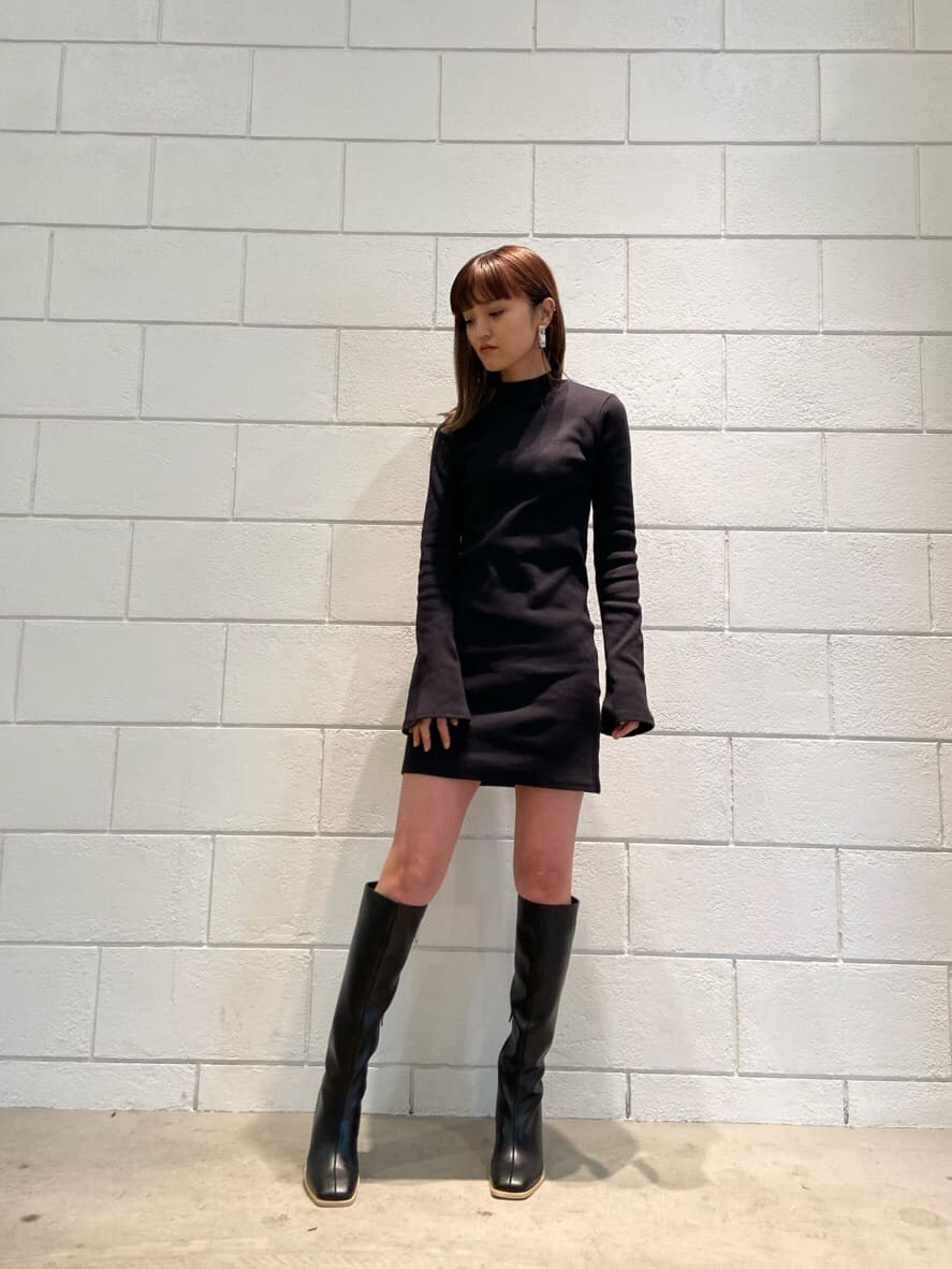 ブラック系のワンピース、ベージュ系のトレンチコート、ブラック系のブーツを着用したレディースの冬コーディネートの5枚目の写真