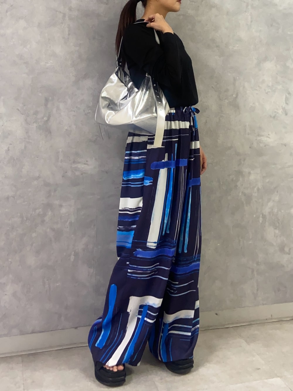 ブラック系のニット/セーター、ブルー系のその他パンツ、シルバー系のショルダーバッグを着用したレディースの秋コーディネートの3枚目の写真