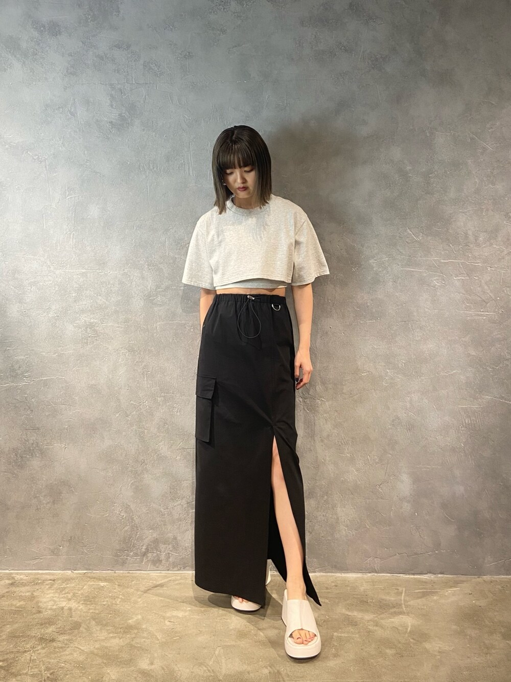グレー系のTシャツ/カットソー、ホワイト系のサンダル、ブラック系のスカートを着用したレディースの春コーディネートの2枚目の写真