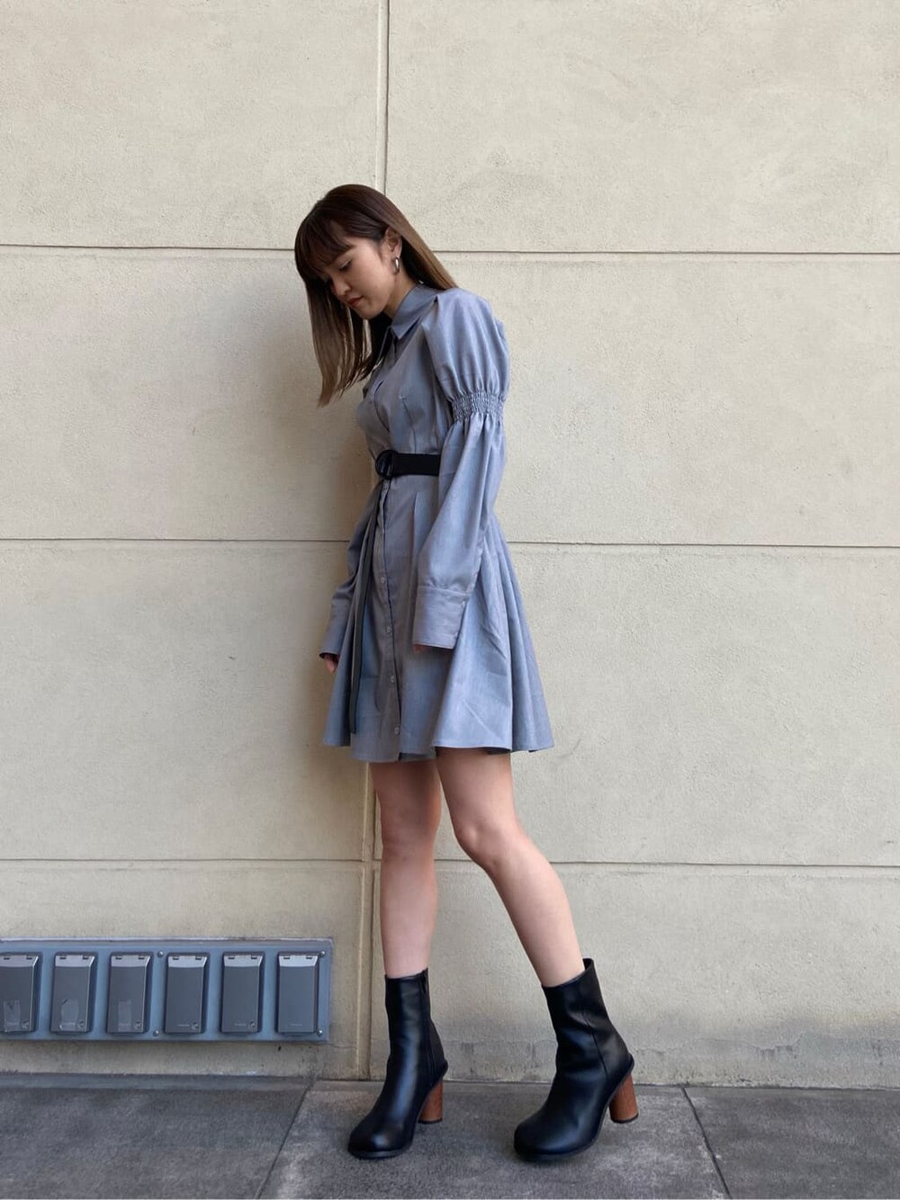 ブラック系のブーツ、グレー系のワンピース、シルバー系のピアス（両耳用）を着用したレディースの春コーディネートの3枚目の写真