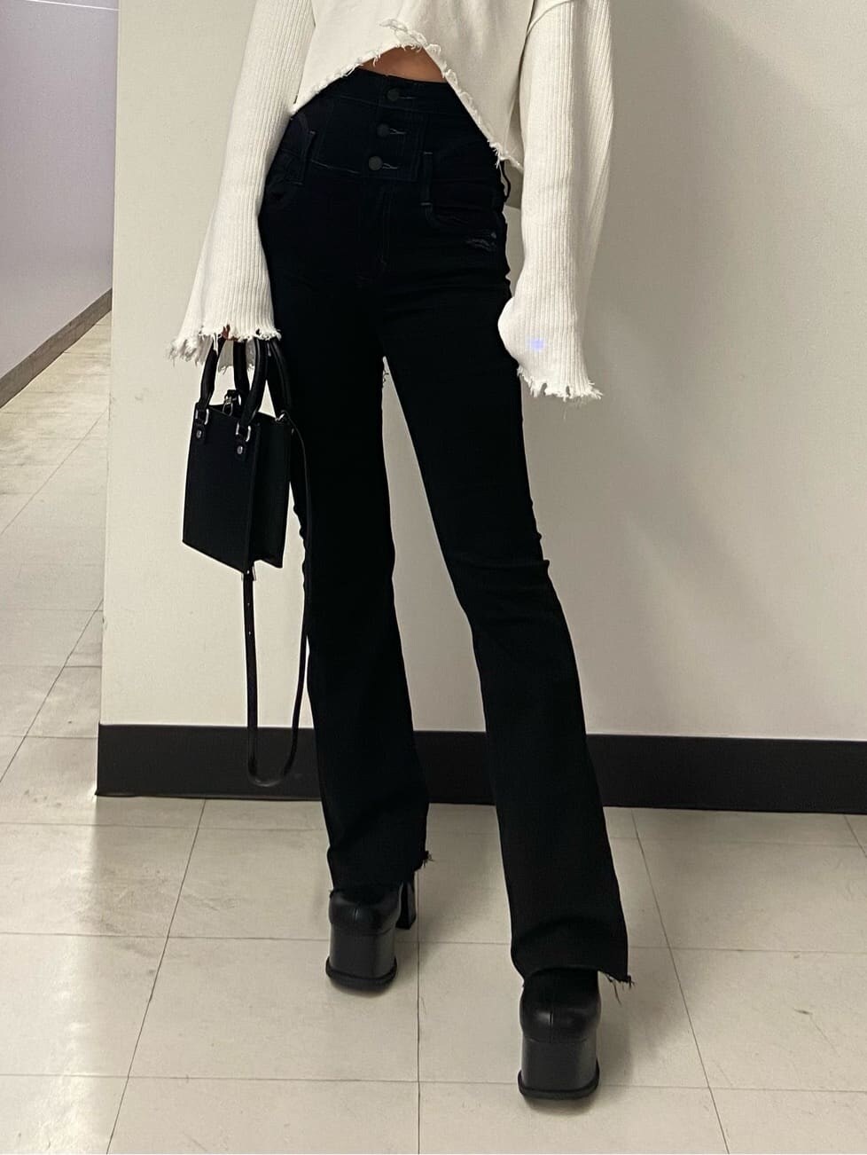 ブラック系のブーツ、ブラック系のハンドバッグ、ホワイト系のカーディガン/ボレロを着用したレディースの秋コーディネートの6枚目の写真