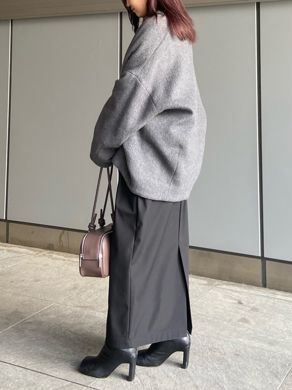 ブラック系のスカート、ブラウン系のボストンバッグ、ブラック系のブーツを着用したレディースの冬コーディネートの2枚目の写真