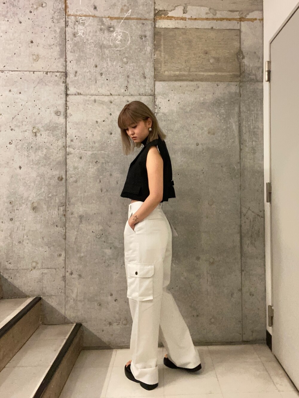 ブラック系のタンクトップ、ホワイト系のカーゴパンツ、ブラック系のサンダルを着用したレディースの夏コーディネートの3枚目の写真
