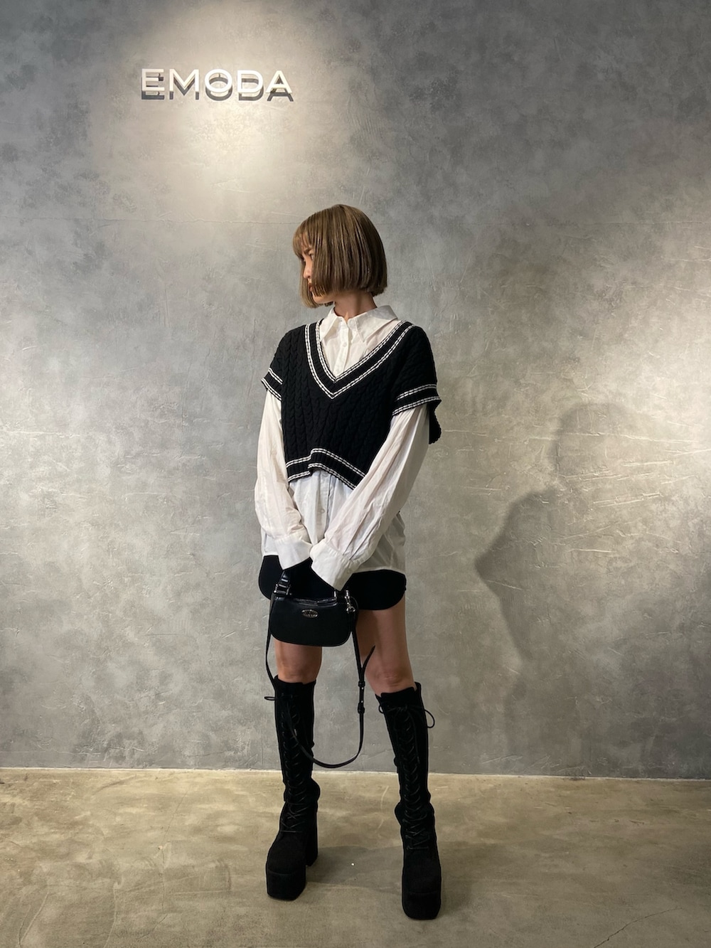 ブラック系のベスト、ホワイト系のシャツ/ブラウス、ブラック系のブーツを着用したレディースの冬コーディネートの2枚目の写真