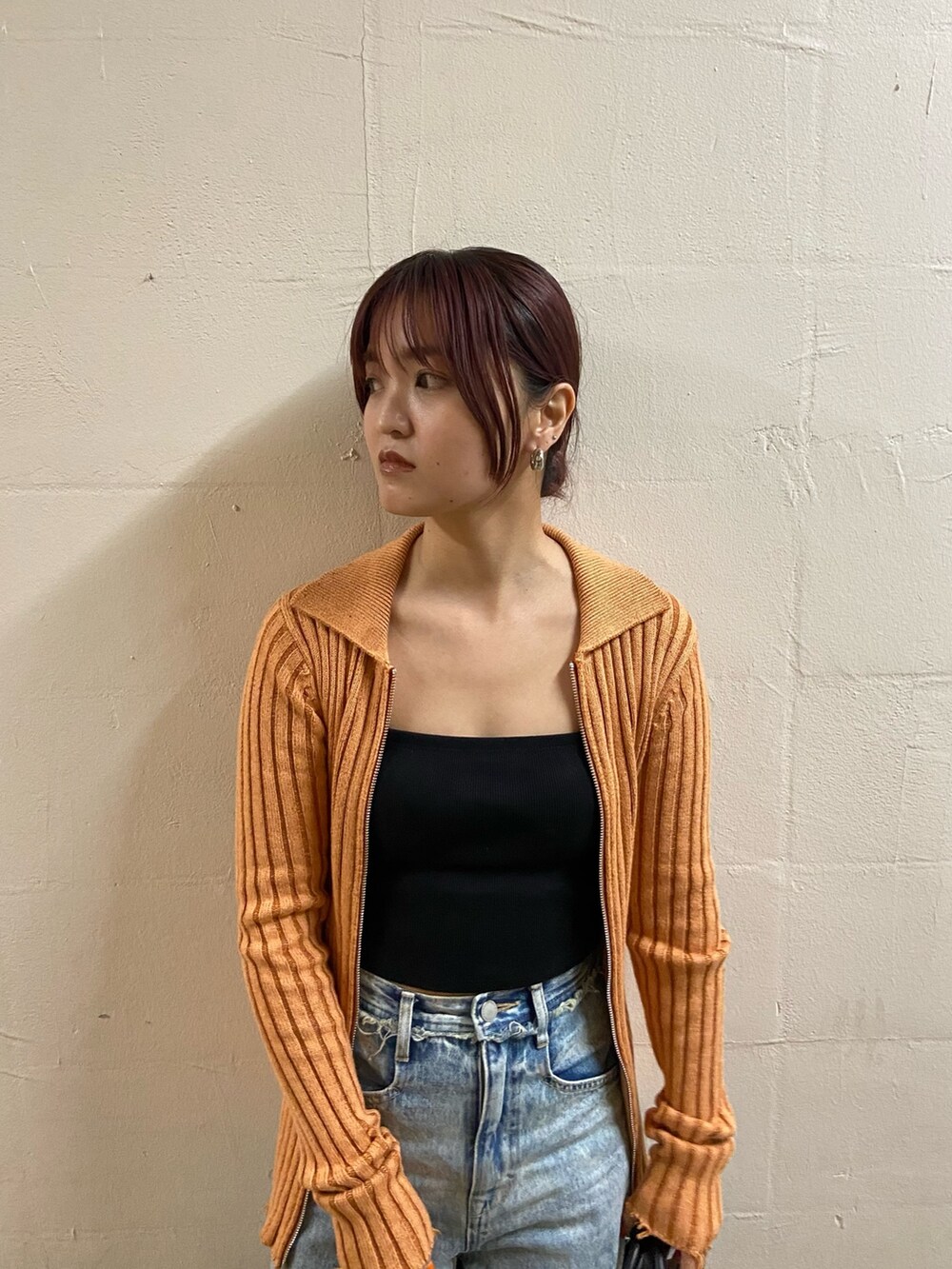 オレンジ系のニット/セーター、ブラック系のキャミソール、ブルー系のデニムパンツを着用したレディースの春コーディネートの3枚目の写真