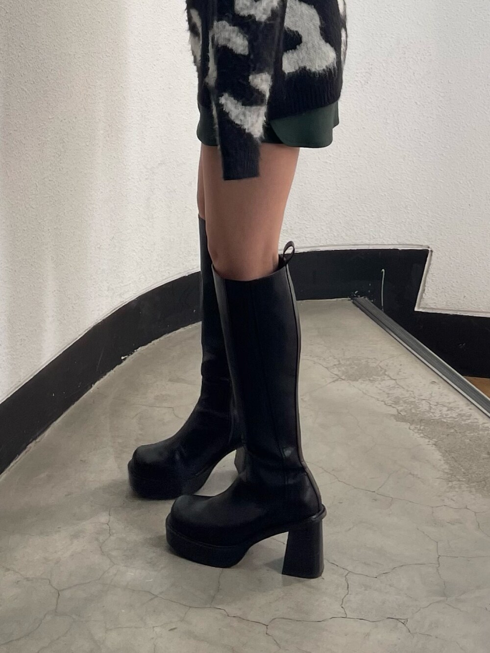 ブラック系のニット/セーター、グリーン系のスカート、ブラック系のブーツを着用したレディースの冬コーディネートの7枚目の写真