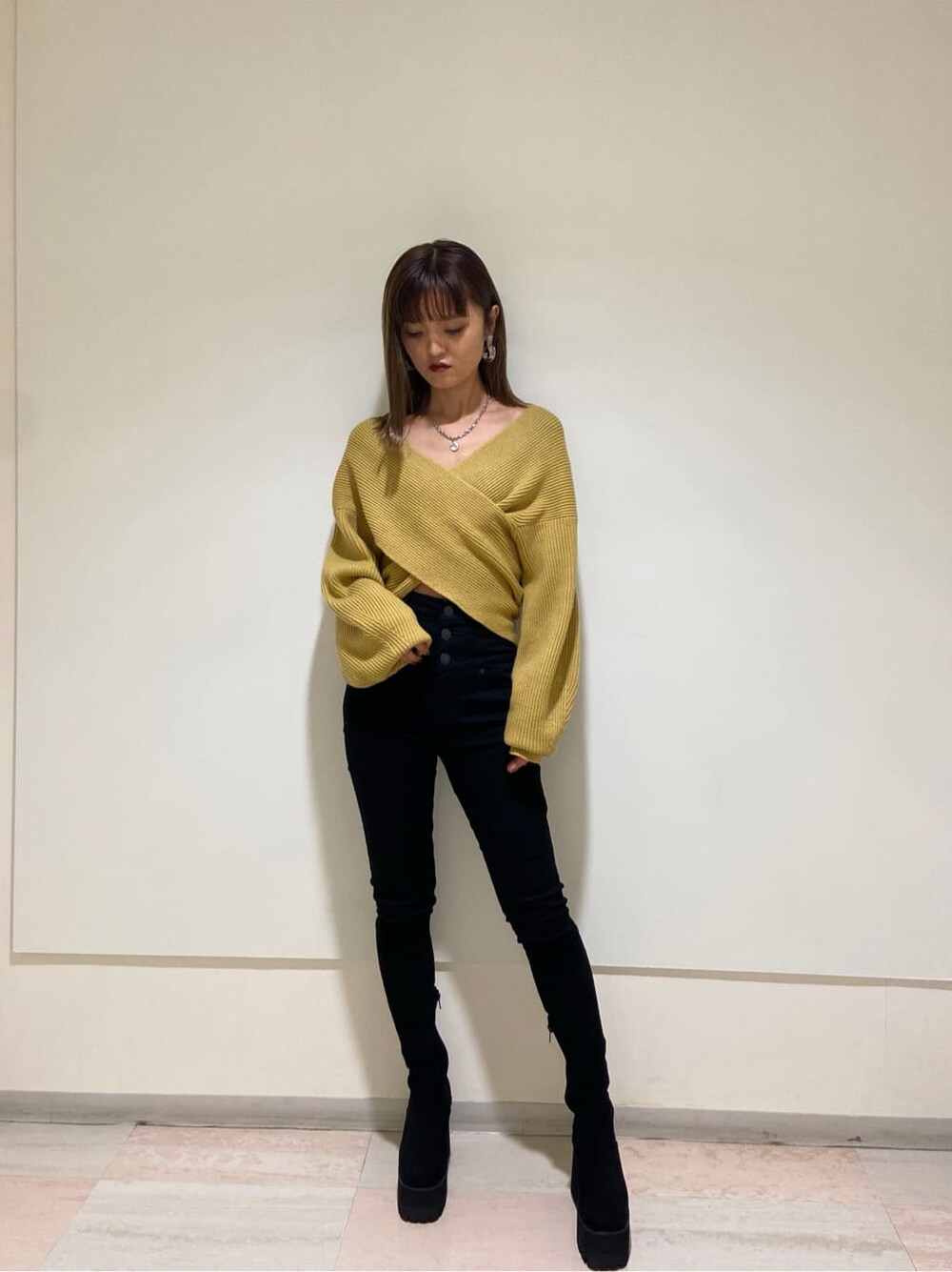 ブラック系のデニムパンツ、ブラック系のブーツ、イエロー系のニット/セーターを着用したレディースの冬コーディネートの5枚目の写真