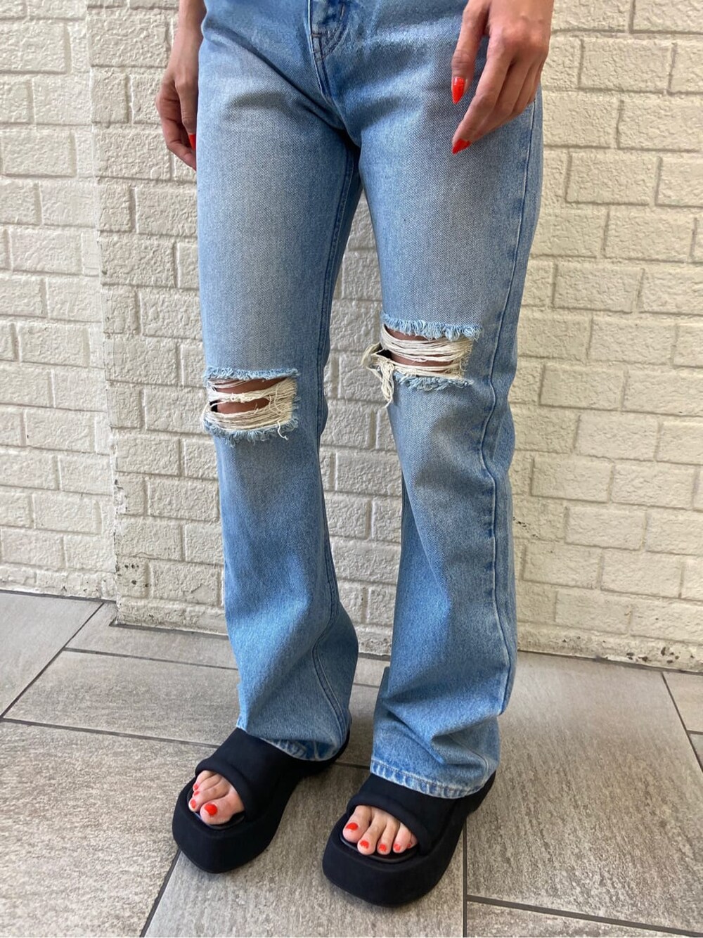 ブルー系のデニムパンツ、ブラック系のサンダル、ホワイト系のシャツ/ブラウスを着用したレディースの夏コーディネートの6枚目の写真