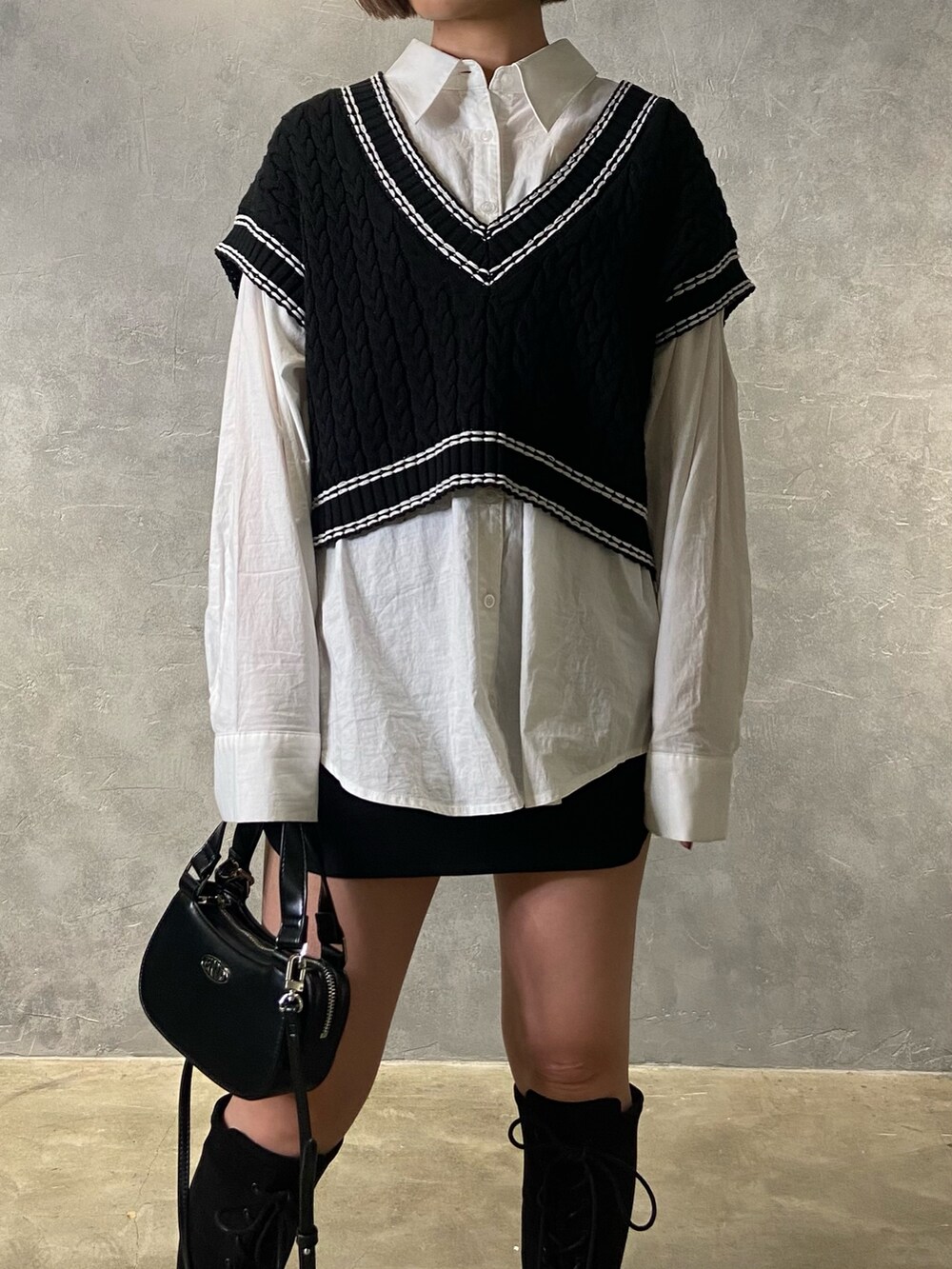 ブラック系のベスト、ホワイト系のシャツ/ブラウス、ブラック系のブーツを着用したレディースの冬コーディネートの5枚目の写真