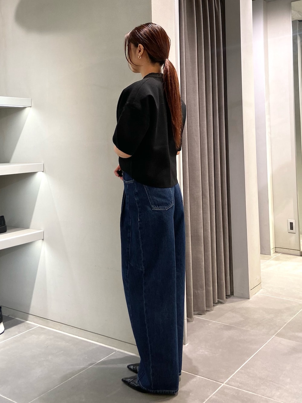 ブラック系のニット/セーター、ブルー系のデニムパンツ、ブラック系のパンプスを着用したレディースの春コーディネートの2枚目の写真