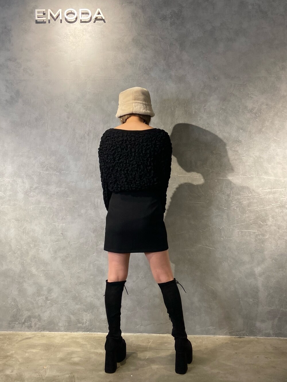 ブラック系のTシャツ/カットソー、ブラック系のスカート、ブラック系のブーツを着用したレディースの冬コーディネートの4枚目の写真