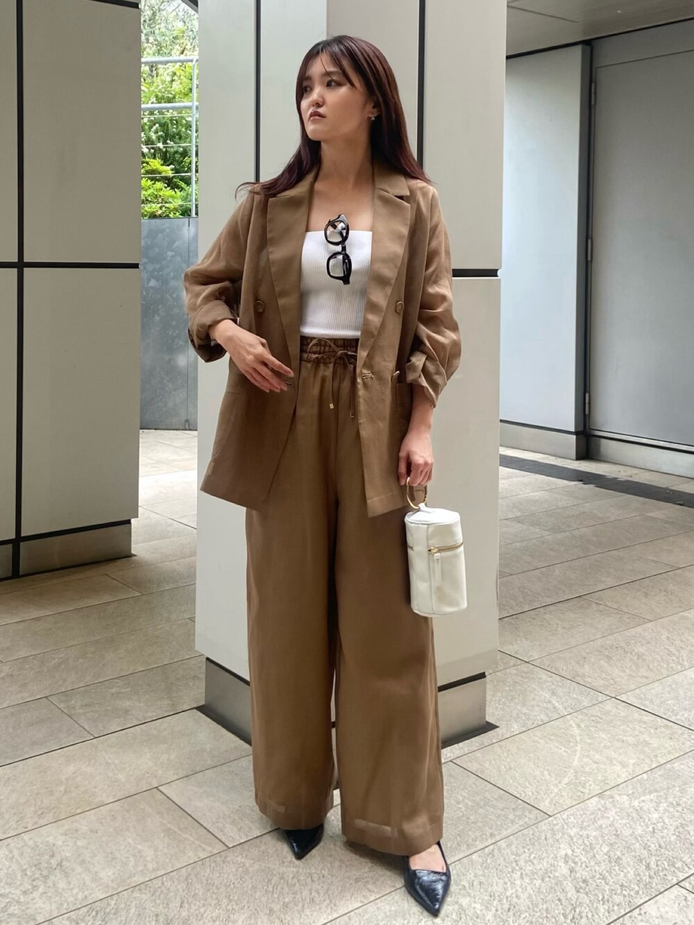 ブラウン系のその他パンツ、ブラック系のサンダル、ホワイト系のキャミソールを着用したレディースの春コーディネートの2枚目の写真