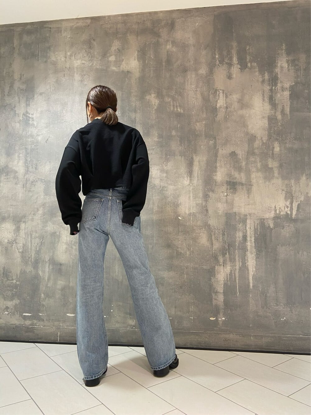 ブラック系のブーツ、ブラック系のTシャツ/カットソー、ブルー系のデニムパンツを着用したレディースの秋コーディネートの4枚目の写真