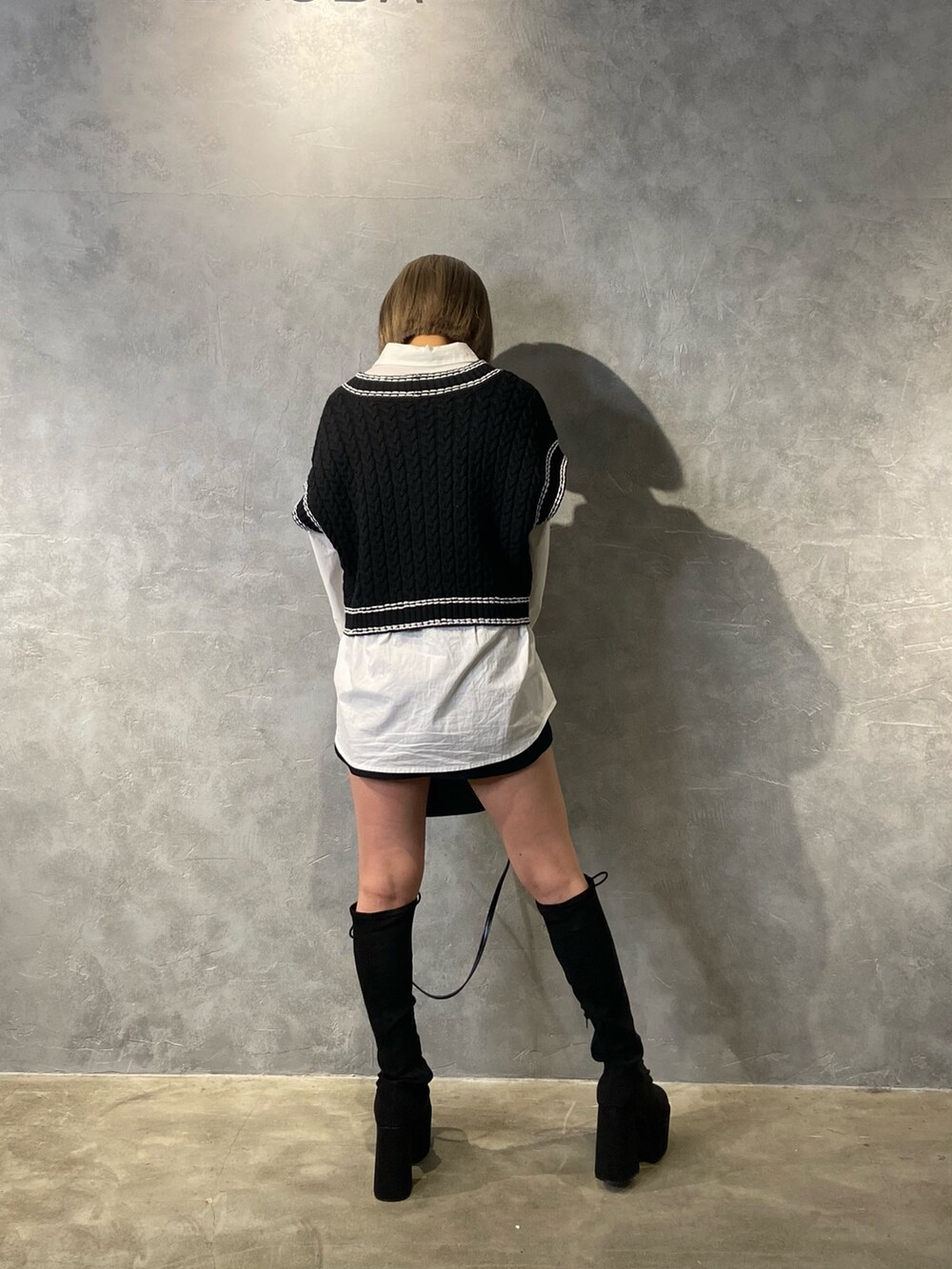 ブラック系のベスト、ホワイト系のシャツ/ブラウス、ブラック系のブーツを着用したレディースの冬コーディネートの4枚目の写真