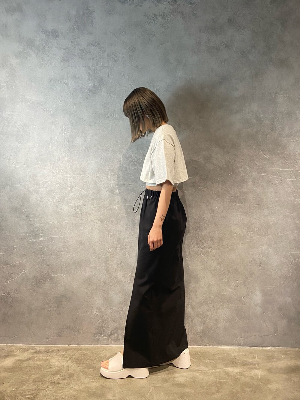 グレー系のTシャツ/カットソー、ホワイト系のサンダル、ブラック系のスカートを着用したレディースの春コーディネートの3枚目の写真