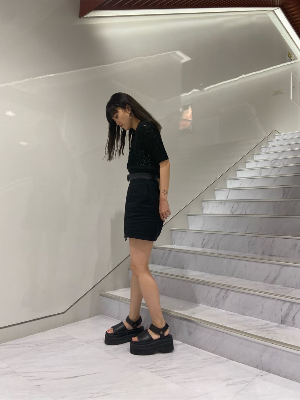 ブラック系のサンダル、ブラック系のニット/セーター、ブラック系のスカートを着用したレディースの夏コーディネートの3枚目の写真