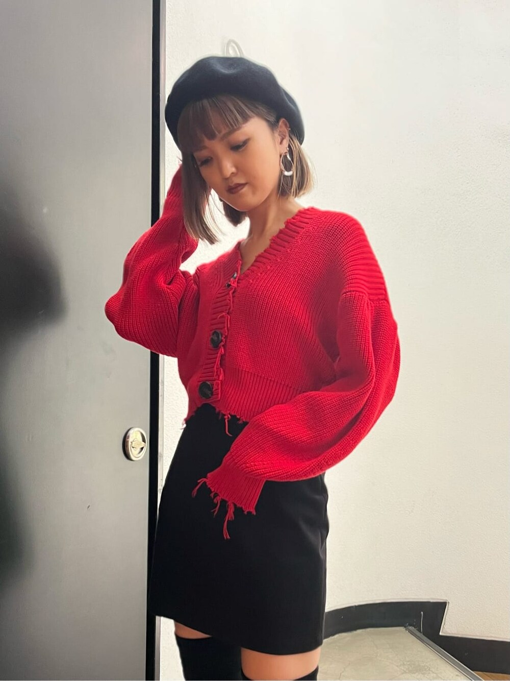 ブラック系のスカート、レッド系のカーディガン/ボレロ、ブラック系のブーツを着用したレディースの秋コーディネートの4枚目の写真