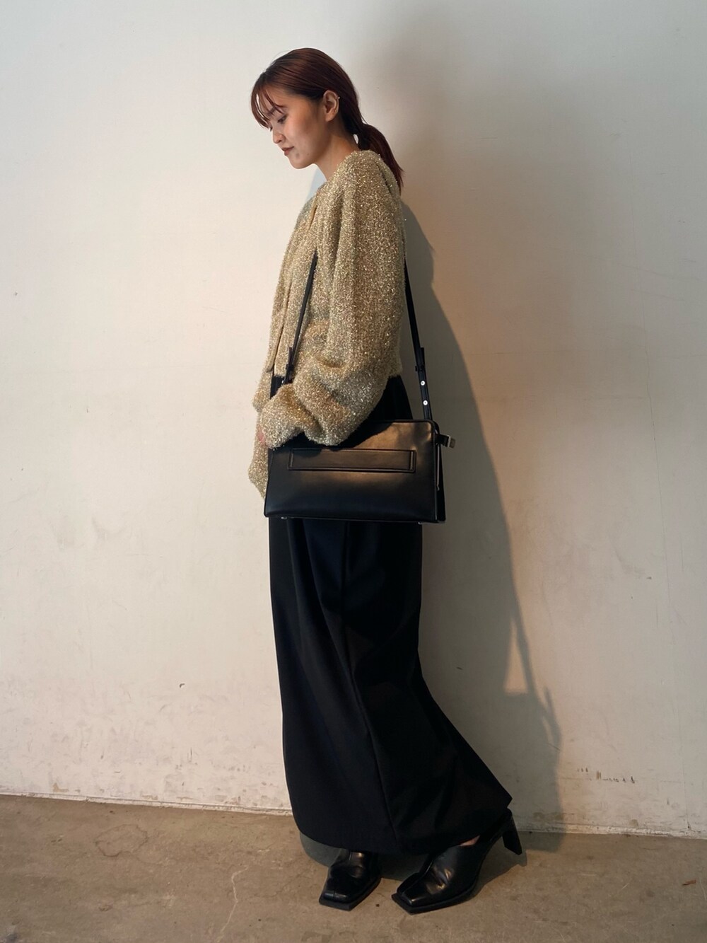 ゴールド系のカーディガン/ボレロ、ブラック系のスカート、ブラック系のサンダルを着用したレディースの冬コーディネートの2枚目の写真