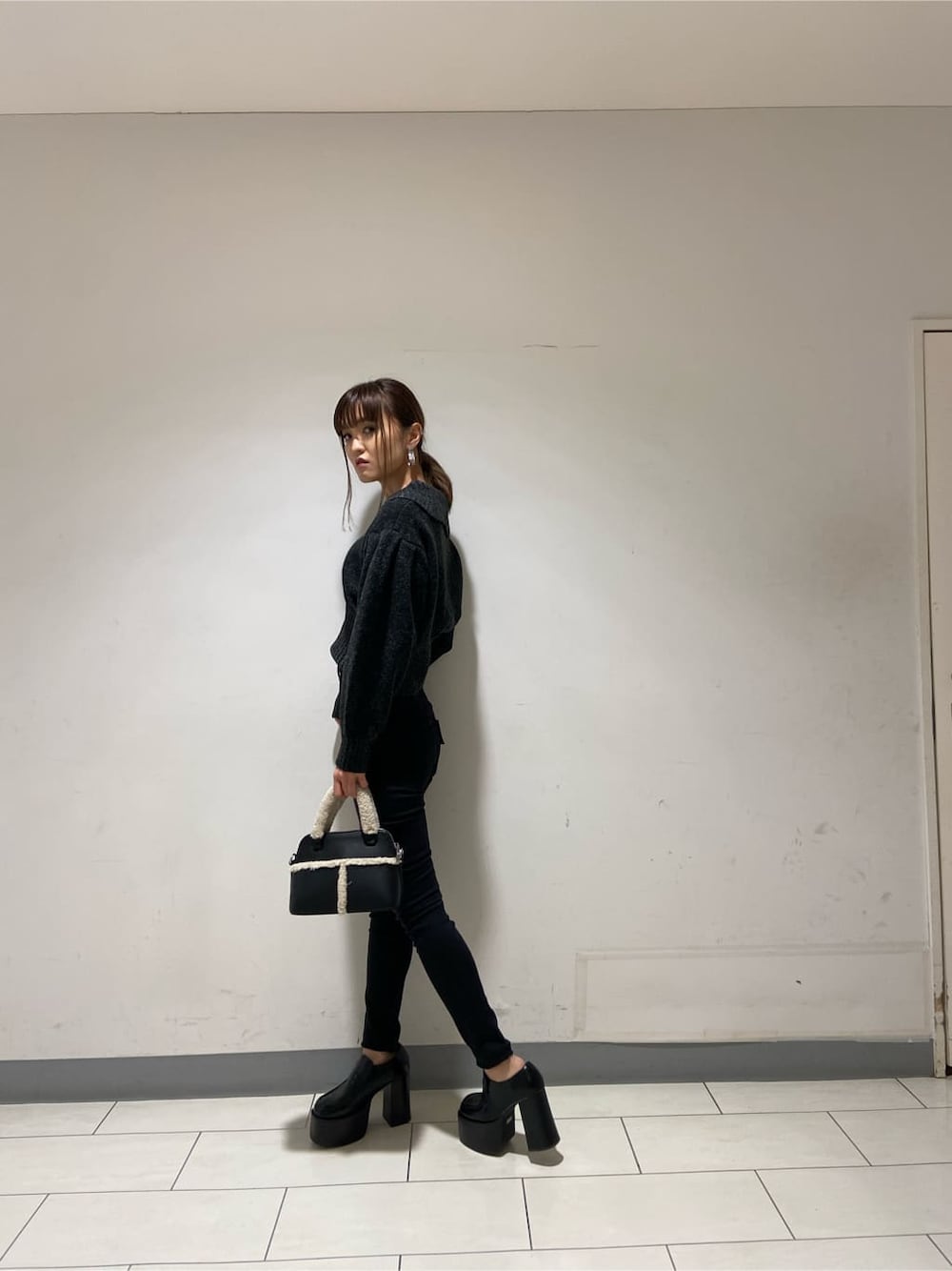 ブラック系のローファー、ブラック系のニット/セーター、ブラック系のデニムパンツを着用したレディースの冬コーディネートの6枚目の写真