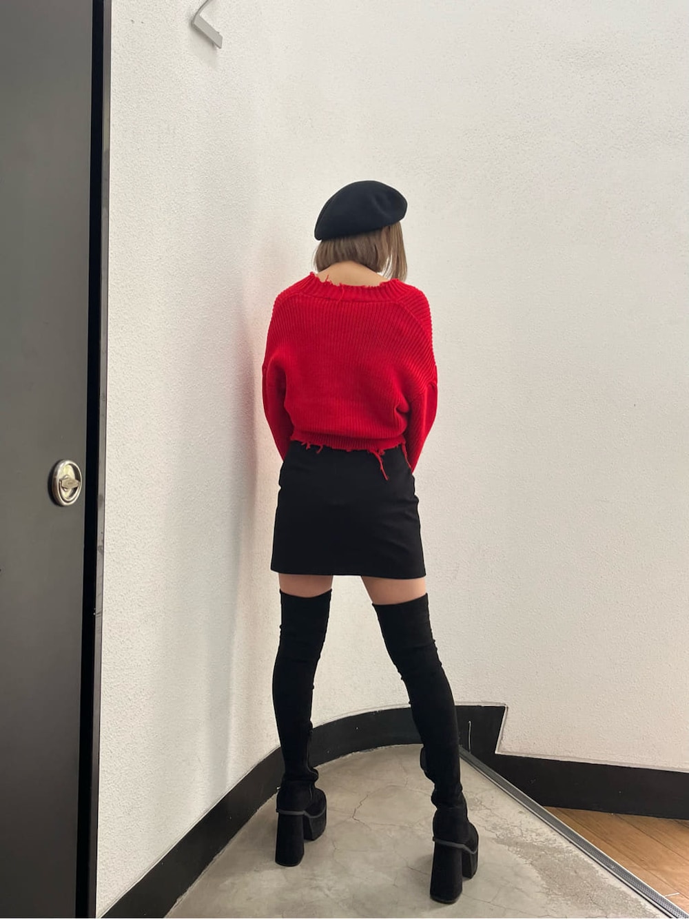 ブラック系のスカート、レッド系のカーディガン/ボレロ、ブラック系のブーツを着用したレディースの秋コーディネートの3枚目の写真
