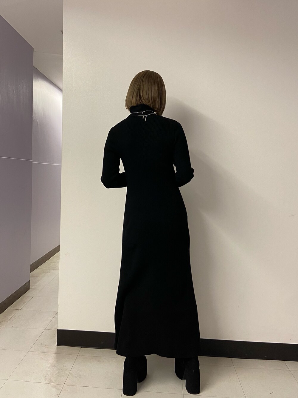 ブラック系のワンピース、ホワイト系のショルダーバッグ、ブラック系のブーツを着用したレディースの秋コーディネートの4枚目の写真